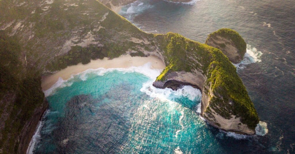 Stunning aerial view of Bali's coastline with turquoise waters and lush cliffs.